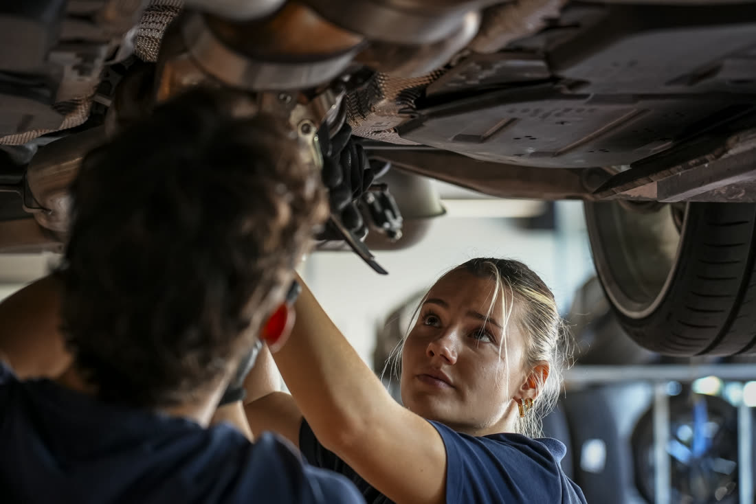 Zwei Mechaniker bei Arbeiten unter einem Fahrzeug auf der Hebebühne